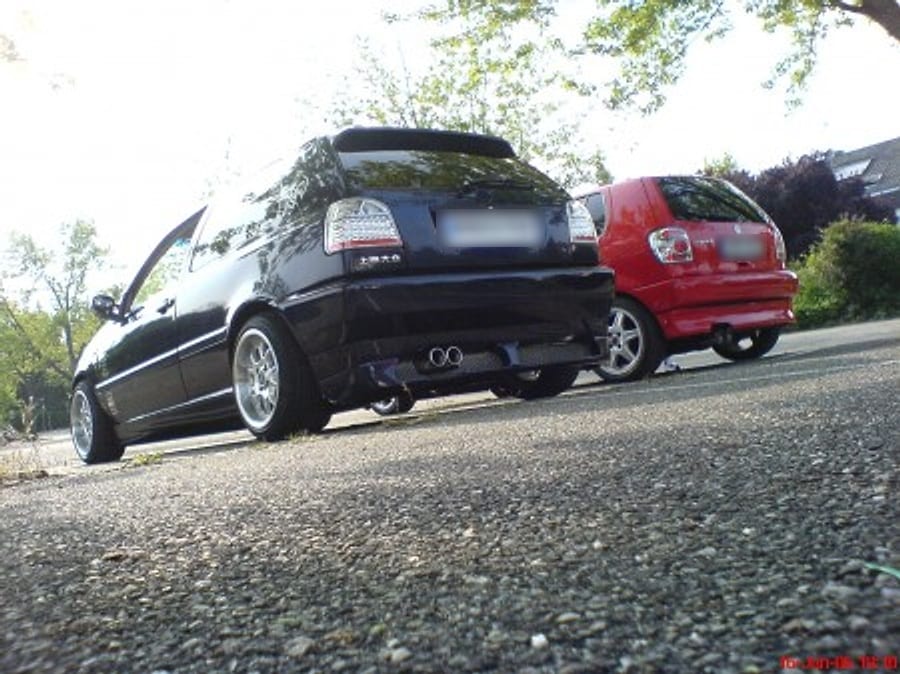 Rear of the VW Golf MK3 with twin exhaust, next to a red hatchback