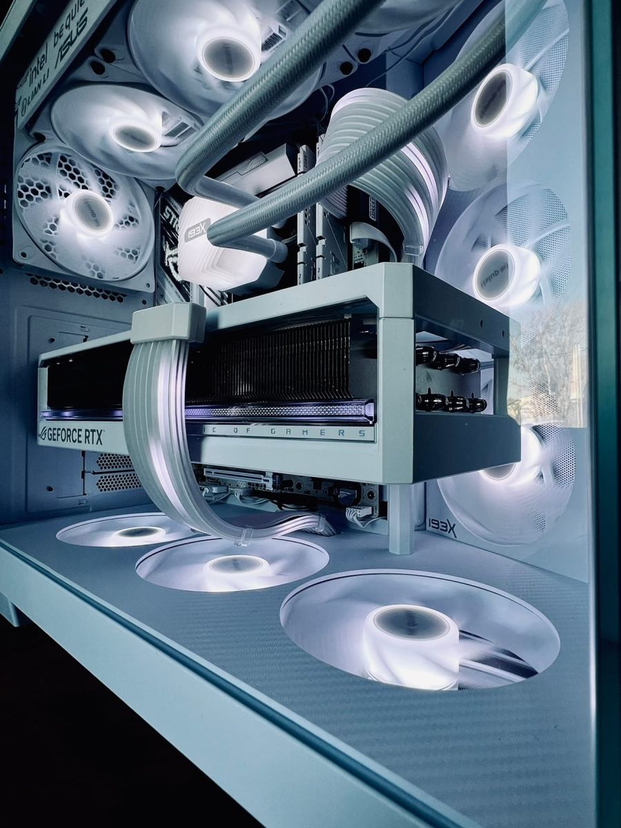 The RTX 5080 ROG Astral sitting in the white build, fans lit