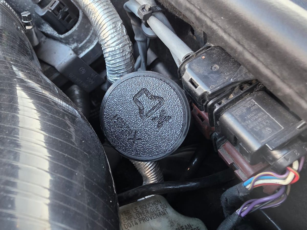 3D-printed cap with a mute icon closing the sound tube in the engine bay of the Audi TT