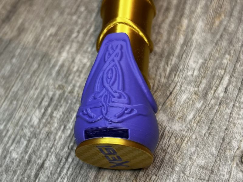 The engraved purple end cap of the gold handle