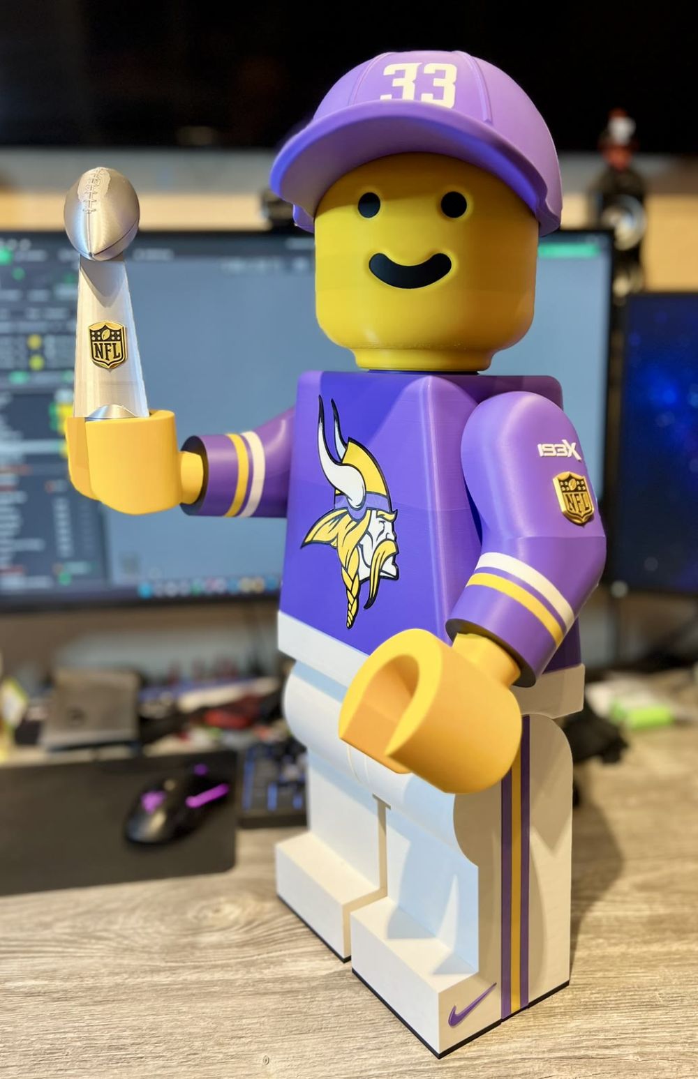 The Brickman holding the Super Bowl trophy, wearing the purple 33 cap