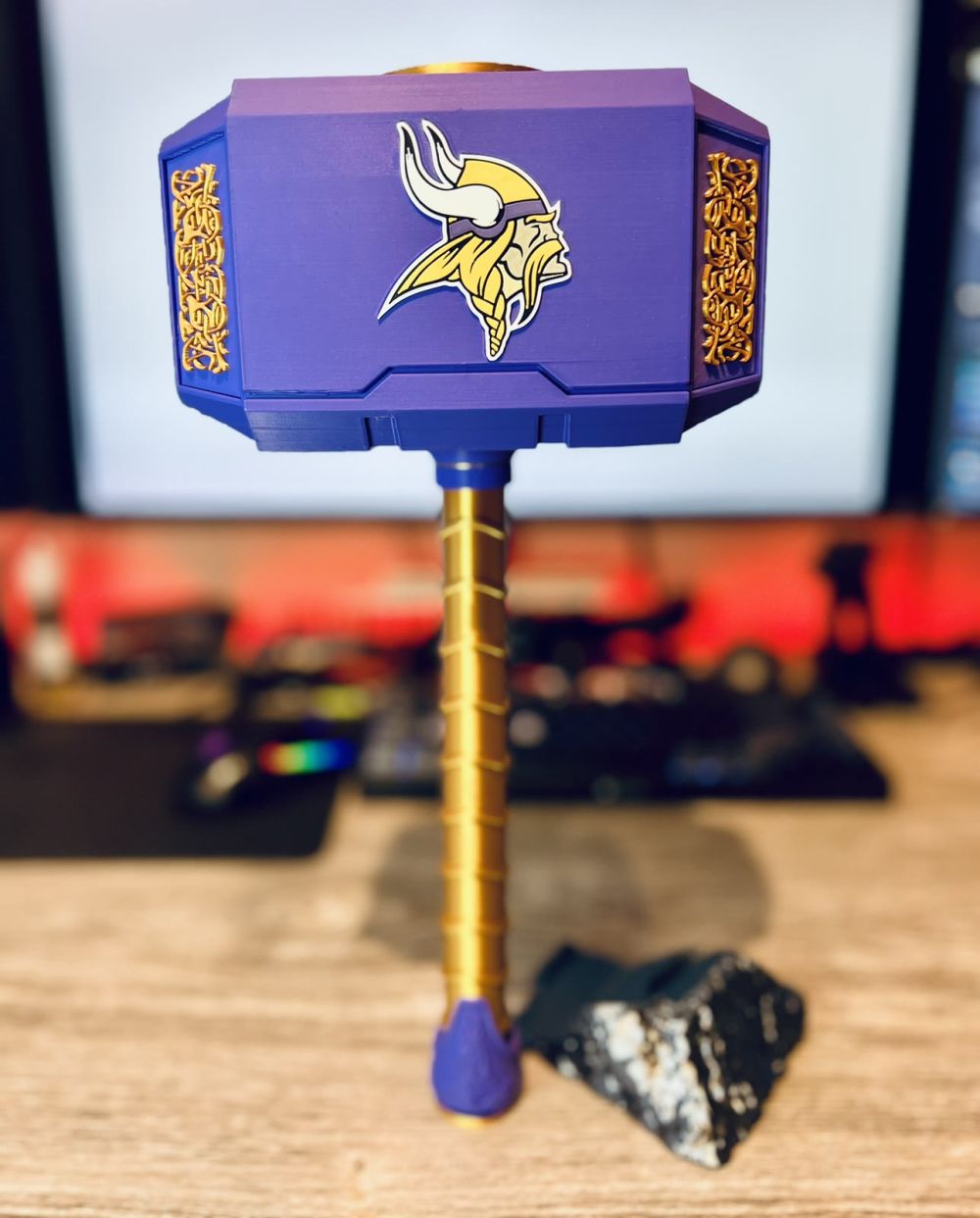 Thor’s hammer in purple and gold resting in its gunmetal rock