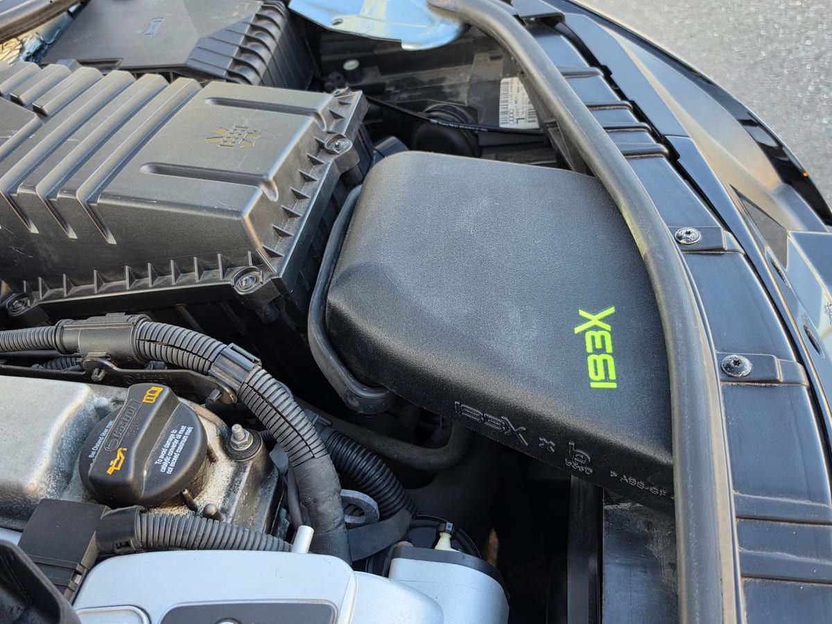 The air intake box with the neon green IBEX logo in the engine bay of the TT