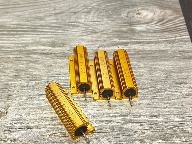 Four gold 100 W load resistors on a wooden desk