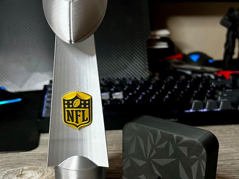The trophy standing on its silver hand adapter next to the black base