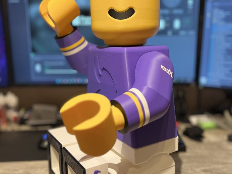 The Brickman raising one arm and one leg