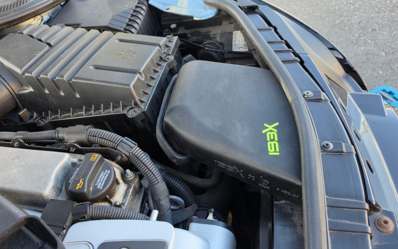 The air intake box with the neon green IBEX logo in the engine bay of the TT